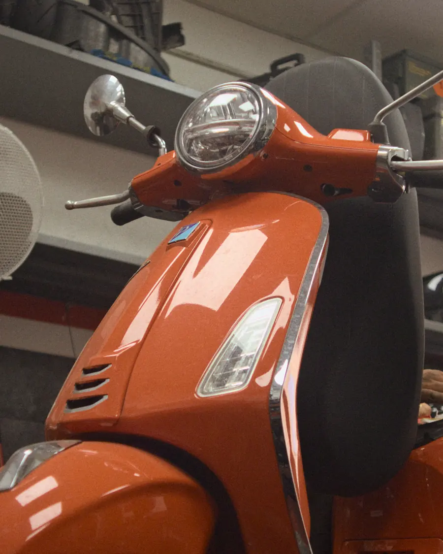 Una Vespa arancione in officina, tra gli scaffali e le gomme