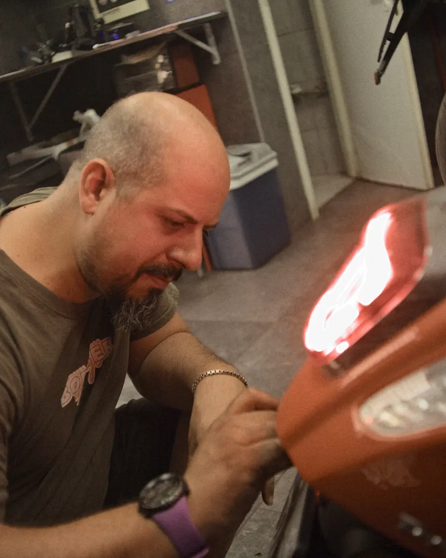 Daniele chino su una Vespa arancione, con la luce rossa del fanale accesa